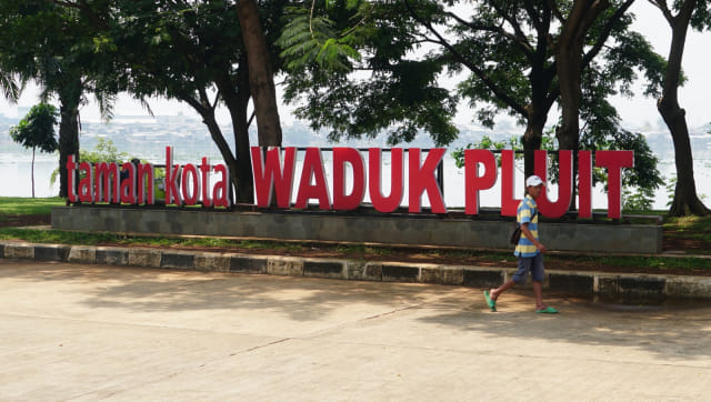 Seorang pejalan kaki sedang melintasi Taman Kota Waduk Pluit. Foto: Nugroho Sejati/kumparan