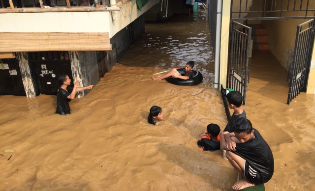 Anak-anak bermain air banjir di Kampung Pulo. Foto: Darin Atiandina/kumparan