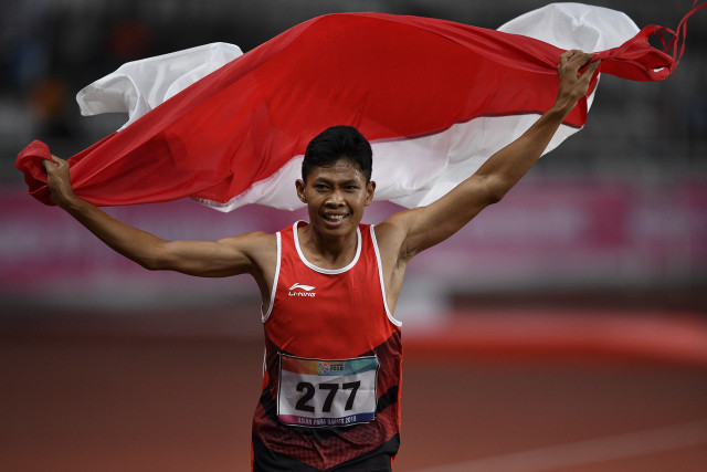 Sprinter Indonesia Sapto Yogo Purnomo membawa bendera Merah-Putih usai menjuarai final 100 meter putra T37 Asian Para Games di Stadion Utama Gelora Bung Karno, Senayan, Selasa (9/10). Foto: ANTARA FOTO/Sigid Kurniawan