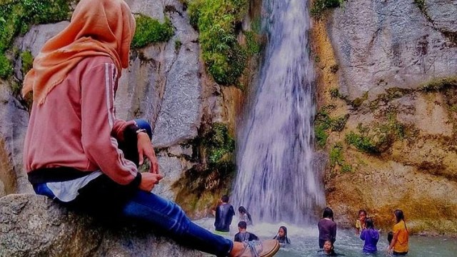 Salah seorang pengunjung duduk santai dan beberapa orang lainnya menikmati pesona alam air terjun Loli Tasiburi, di Desa Loli Tasiburi, Kecamatan Banawa, Kabupaten Donggala, Sulawesi Tengah. Foto: Istimewa