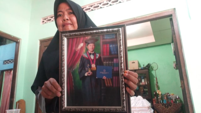 Mela Siti Malikah (32) menunjukkan foto almarhum suaminya, Agung Nugroho, yang meninggal dunia pada Minggu (28/4/2019). (Agung Santoso)