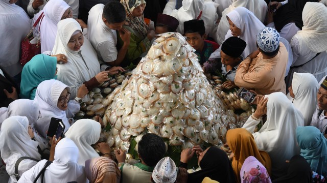 Warga bersiap-siap membagikan kue apem saat digelar 'Megengan Kubro' di Masjid Al Akbar Surabaya, Jawa Timur, Jumat (3/5/2019). Foto: ANTARA FOTO/Zabur Karuru