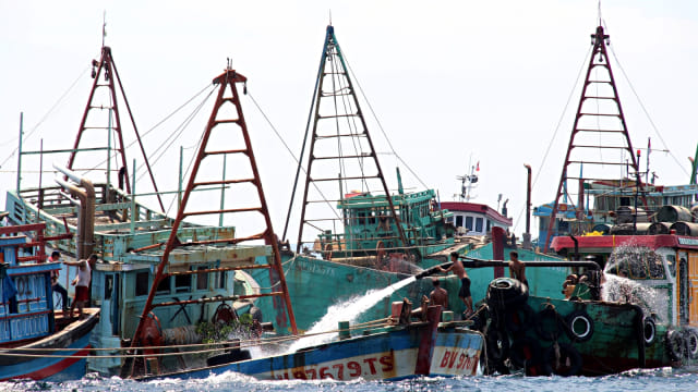 Sejumlah anak buah kapal bantu menyemprotkan air menggunakan mesin pompa ke dalam kapal nelayan Vietnam. Foto: Antara/Jessica Helena Wuysang