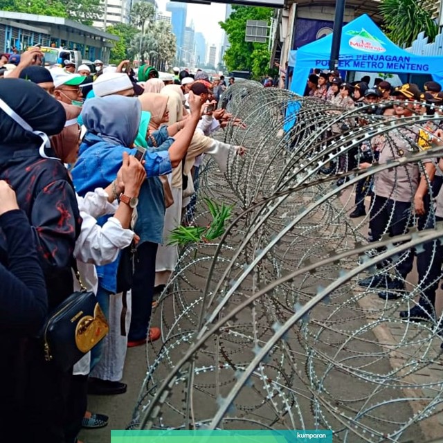 Sejumlah ibu-ibu menarik kawat berduri yang terpasang di depan gedung Bawaslu saat melakukan aksi demo. Foto: Lutfan Darmawan/kumparan