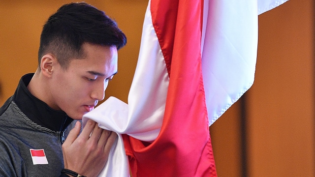 Pebulu tangkis putra Indonesia Jonatan Christie mencium bendera Merah Putih saat prosesi pelepasan Tim Piala Sudirman 2019. Foto: Antara/Sigid Kurniawan