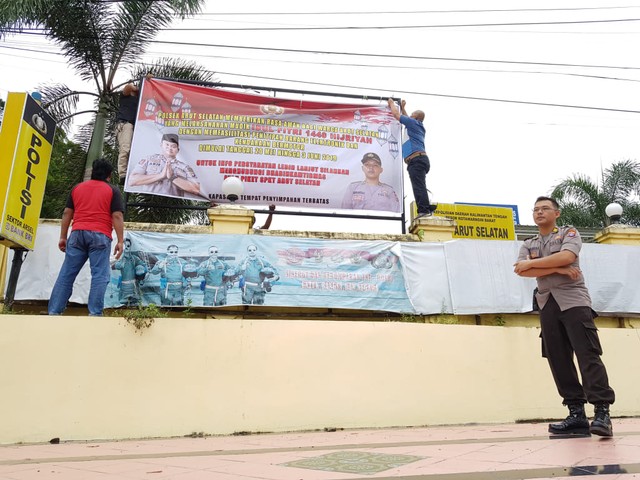 Kapolsek Arsel AKP Hendra Aditia Dani beserta jajaran memasang spanduk penitipan motor di Mapolsek Arsel. (Foto: Joko Hardyono)