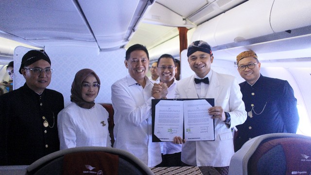 Direktur Utama PT Pegadaian (Persero), Kuswiyoto (ketiga kiri) bersalaman dengan Direktur Utama Garuda Indonesia, Ari Askhara pada penandatanganan kerja sama komersial dalam penerbangan Jakarta-Denpasar. Foto: Dok. Garuda Indonesia
