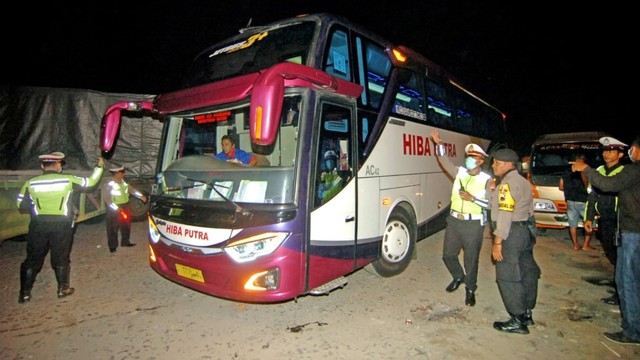 Polisi memberhentikan bus dari arah Jawa Tengah menuju Jakarta saat razia penyekatan massa di jalur Pantura, Maribaya, Kabupaten Tegal, Jawa Tengah, Minggu (19/5/2019) malam. Foto: ANTARA FOTO/Oky Lukmansyah