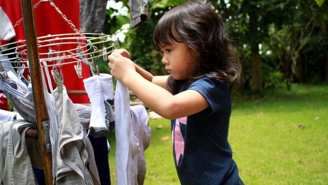 Anak balita membantu ibu menjemur pakaian Foto: Shutterstock