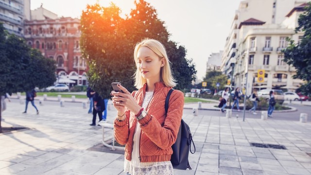 Traveler menggunakan ponsel sambil berjalan Foto: Shutter Stock