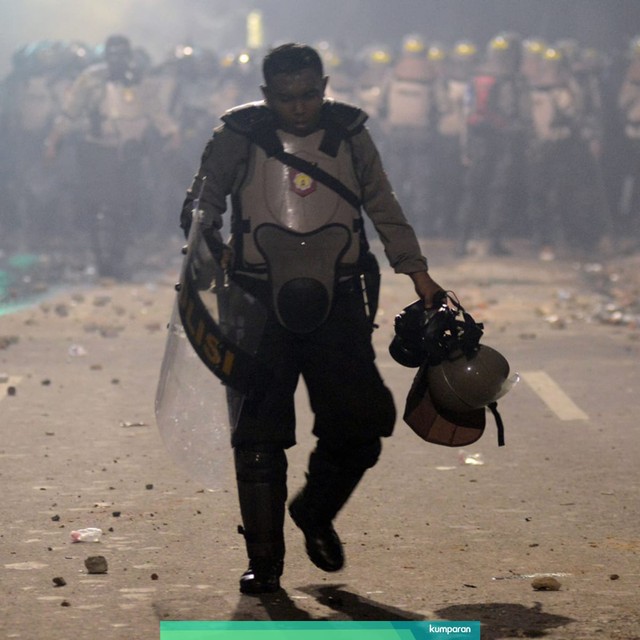 Seorang anggota kepolisian berjalan keluar dari barisan barikade saat kericuhan Aksi 22 Mei terjadi di Jalan Brigjen Katamso, Slipi, Jakarta, Rabu (22/5). Foto: ANTARA FOTO/M Risyal Hidayat