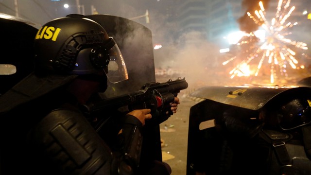 Seorang anggota kepolisian menembakan gas air mata ke arah pengunjuk rasa saat terjadi kerusuhan di dekat kantor Bawaslu, Jakarta, Rabu (22/5). Foto: REUTERS / Willy Kurniawan