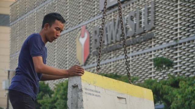 Seorang petugas mengangkut separator beton yang menutup Jalan MH Thamrin, Jakarta. Foto: Irfan Adi Saputra/kumparan