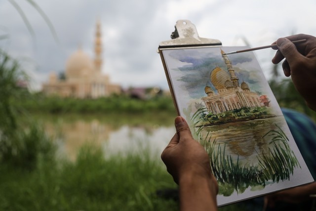 Tangan Iswadi Basri menuntun kuas kecil di atas kertas melukis Masjid Haji Keuchik Leumik yang berdiri megah di pinggir Krueng Aceh. Foto: Suparta/acehkini 