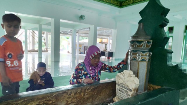 Ema, warga Sigi, mengajak serta anak-anaknya berziarah ke makam Al-Habib Idrus bin Salim Al-Jufri di Masjid Alkhairaat di Jalan Sis Aljufri, Kelurahan Kamonji, Kecamatan Palu Barat, Kota Palu, Jumat (7/6). Foto: Palu Poso