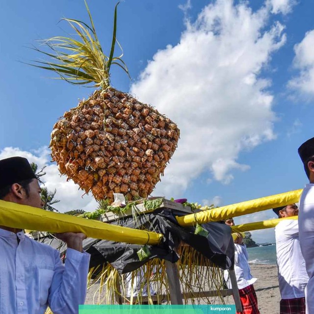 Sejumlah laki-laki mengangkat "topat" (ketupat) untuk disajikan saat mengikuti tradisi lebaran topat di pantai Batulayar, Lombok Barat, NTB, Rabu (12/6). Foto: ANTARA FOTO/Ahmad Subaidi
