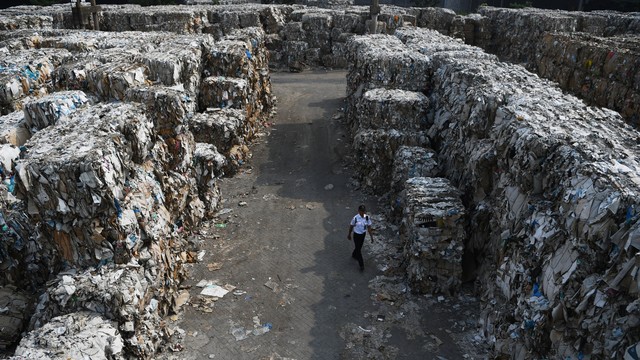 Petugas melintas di antara tumpukan sampah kertas yang diimpor oleh sebuah perusahaan pabrik kertas sebagai bahan baku kertas di Mojokerto, Jawa Timur, Rabu (19/6). Foto: ANTARA FOTO/Zabur Karuru