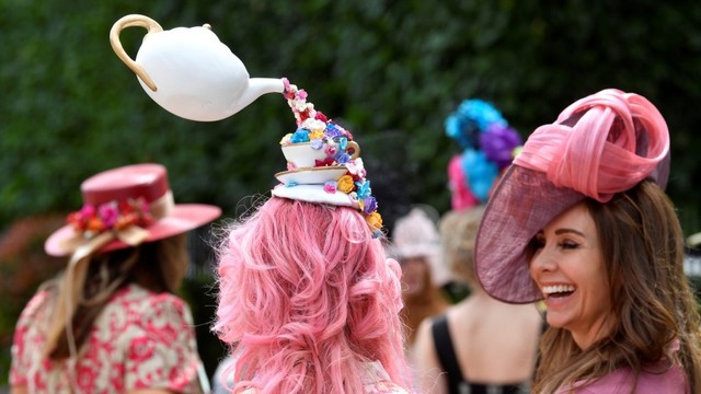 Seorang pebalap pacuan kuda memakai topi berbentuk teko menuangkan air menghadiri pacuan kuda Royal Ascot, di Ascot. Inggris. Foto: REUTERS / Toby Melville