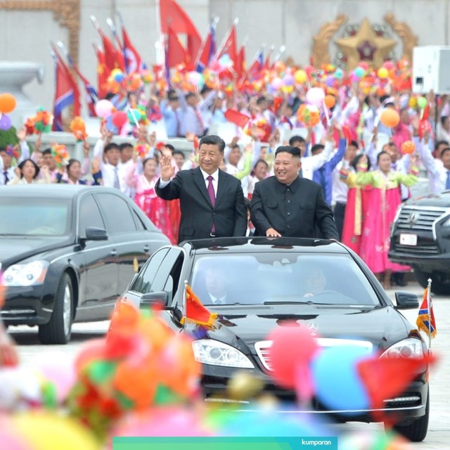 Pemimpin Korea Utara Kim Jong Un (kanan)  dan Presiden China Xi Jinping (kiri) menyapa warga selama pertemuan di Pyongyang, Korea Utara. Foto: Reuters/KCNA