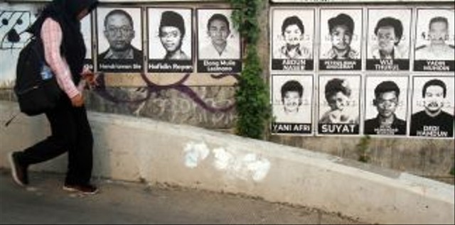 Warga melintas di depan poster aktivis yang hilang di kawasan Beji. Foto: ANTARA FOTO/Yulius Satria Wijaya