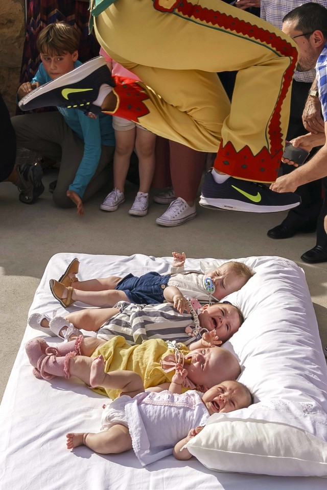 Colacho, karakter yang mewakili iblis, melompati bayi pada festival 'El Colacho' di desa Castrillo de Murcia, Spanyol, Minggu (23/6). Foto: AFP/CESAR MANSO
