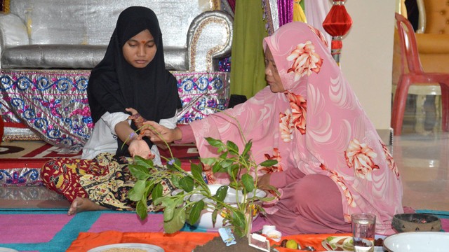 Hulango (dukun beranak) memberikan bontho (titik) pada si gadis di bagian tubuh tertentu dengan campuran bedak dan rempah yang sudah dihaluskan. Jumat (5/7). Foto: Burdu/banthayoid