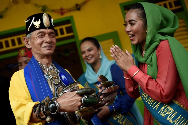 Seorang perwakilan Abang None menyambut pengunjung dengan mengenakan pakaian adat Betawi saat Lebaran Betawi 2019 di lapangan silang Monumen Nasional (Monas), Jakarta, Sabtu (20/7). Foto: ANTARA FOTO/M Risyal Hidayat