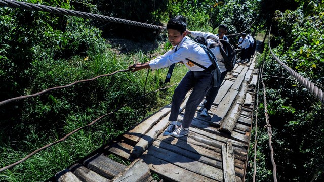 Sejumlah siswa berjalan melawati jembatan gantung yang rusak di Desa Sukamulya, Pandeglang, Banten, Selasa (30/7/2019). Foto: ANTARA FOTO/Muhammad Bagus Khoirunas