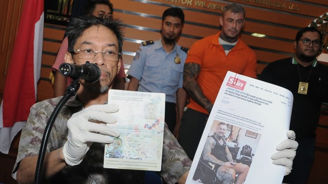 Petugas menunjukkan paspor milik Warga Negara Inggris berinisial TDM (kedua kanan) saat rilis di Kantor Imigrasi Kelas I Khusus Ngurah Rai, Badung, Bali, Selasa (30/7). Foto: ANTARA FOTO/Fikri Yusuf