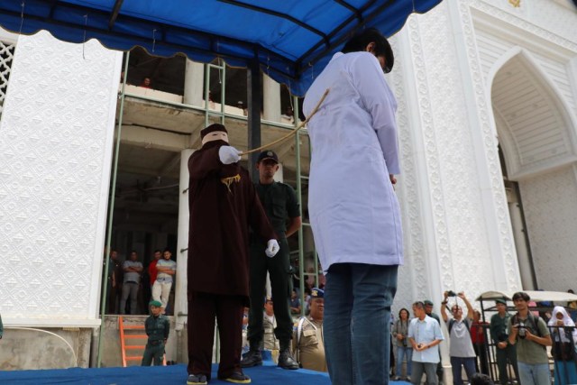Seorang warga menjalani hukuman cambuk di halaman Masjid Baitussalahin, Ulee Kareng, Kota Banda Aceh, Kamis (1/8). Foto: Suparta/acehkini