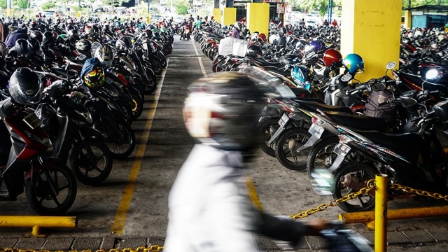 Pengendara motor melintasi parkiran motor. Foto: Nugroho Sejati/kumparan