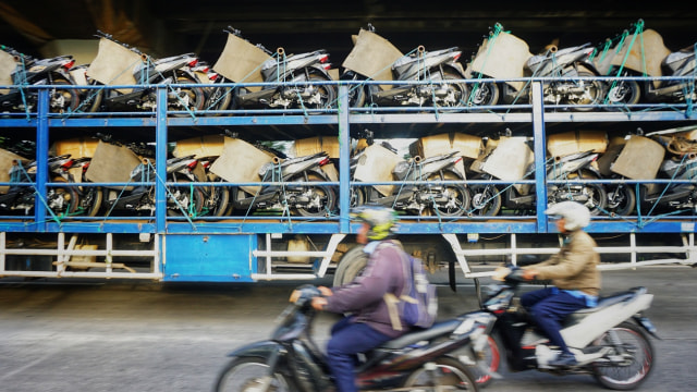 Pengendara motor melintasi mobil truk pengangkut motor. Foto: Nugroho Sejati/kumparan