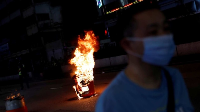Kepulan api terlihat saat demonstran berjalan di Hong Kong. Foto: REUTERS / Tyrone Siu