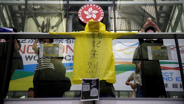 Penumpang menempelkanspanduk dari jas hujan di Bandara Hong Kong yang ditutup karena Demo. Foto: REUTERS/Edgar Su