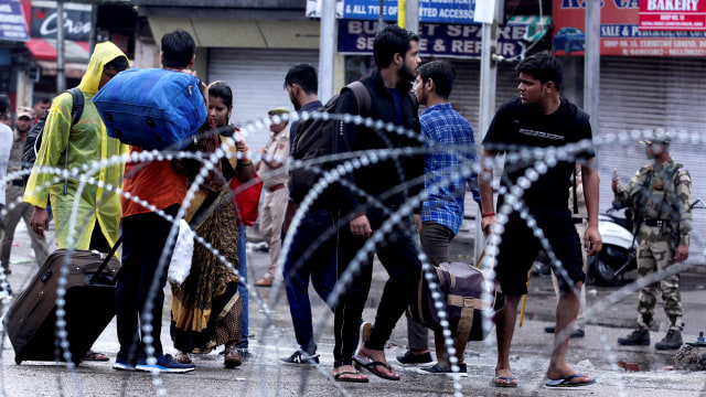 Orang-orang berjalan di sepanjang jalan di Jammu, India. Foto: AFP/RAKESH BAKSHI