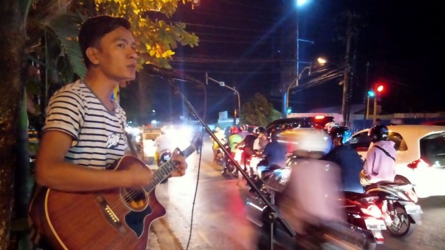 Iskandar sedang mengamen di simpang empat Jalan Gatot Subroto, Kota Banjarmasin. Foto: Donny Muslim/banjarhits.id