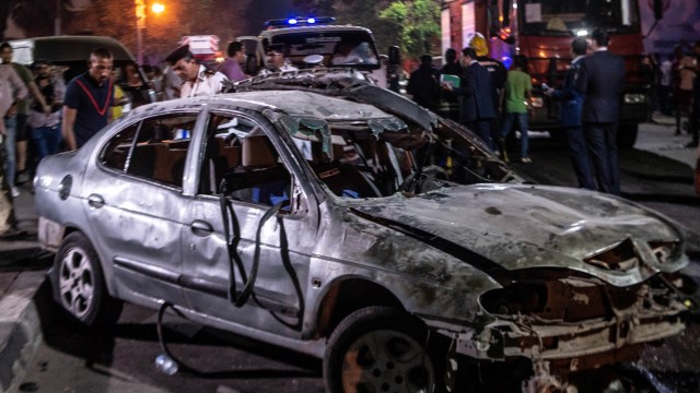 Pasukan keamanan Mesir berkumpul di sekitar mobil yang hancur akibat ledakan di Kairo, Mesir. Foto: AFP/ALY FAHIM
