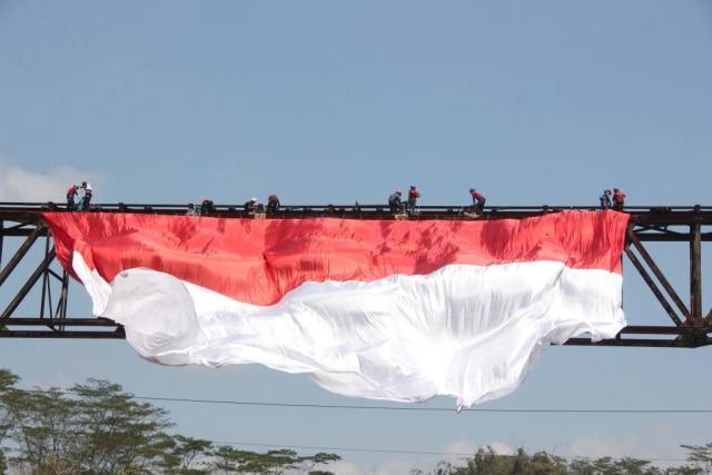 Bendera merah putih raksasa dikibarkan di bekas jembatan kereta api peninggalan Hindia-Belanda yang membentang di Kali Progo Temanggung, Sabtu (17/8/2019). Foto: ari.