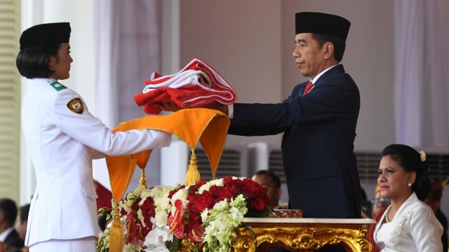 Presiden Joko Widodo (kanan) menerima duplikat bendera pusaka dari Paskibraka pembawa baki Aisyah Rahmawati (kiri) saat memimpin upacara penurunan bendera Merah Putih dalam rangka HUT ke-74 Kemerdekaan RI di Istana Merdeka, Jakarta. Foto: ANTARA FOTO/Wahyu Putro A