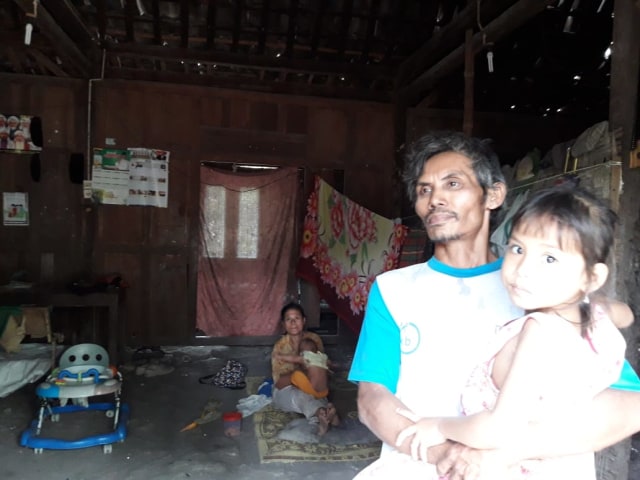 Mujiyo (47) sedang menggendong anaknya. Foto: erl.