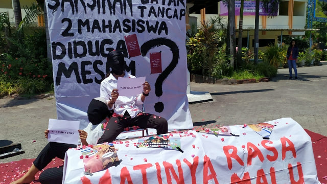 Dua orang mahasiswa Universitas Dr Soetomo (Unitomo) Surabaya saat gelar aksi protes berupa pertunjukan seni menutup kepala dengan kain hitam, Jumat (6/9).  Foto: Yuana Fatwalloh/kumparan