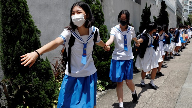 Para pelajar Sekolah Menengah Pertama memegang tangan tanda Rantai Manusia sebagai simbol demo anti pemerintah Hong Kong. Foto: REUTERS