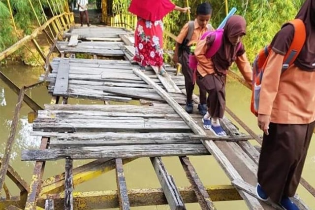 Siswa melintas di jembatan yang sudah rusak untuk menuju ke sekolah. Foto: Jawahir untuk acehkini