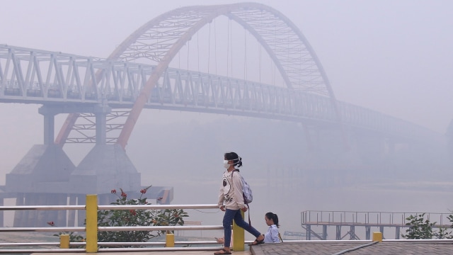 Warga menggunakan masker saat berada di objek wisata bantaran Sungai Kahayan, Palangka Raya, Kalimantan Tengah, Minggu (15/9/2019). Foto: ANTARA FOTO/Rendhik Andika