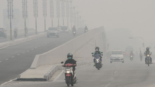 Pengendara kendaraan bermotor melintas di jalan Soekarno Hatta ketika kabut asap pekat dampak karhutla menyelimuti Kota Pekanbaru, Riau, Selasa (17/9/2019). Foto: ANTARA FOTO/Rony Muharrman
