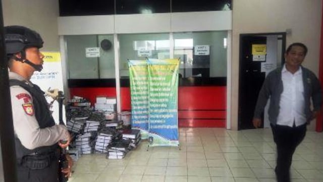 Seorang pegawai melintas di depan petugas kepolisian yang berjaga saat tim KPK menggeledah kantor OPD Kepri. (Foto: Sutana/batamnews)