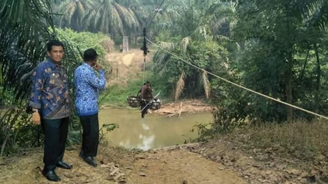 Camat Tambusai, Rokan Hulu, Muammer Ghadafi, saat melihat warga menyebrangi Batang Kumu selebar lebih 50 meter menggunakan sepeda motor ditarik kabel sling Flying Fox. (Foto: Koleksi Pribadi)