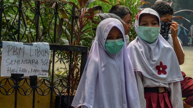 Murid Sekolah Dasar dipulangkan ke rumah akibat kabut asap di Pekanbaru, Riau pada 10 September 2019. Foto: AFP/Wahyudi