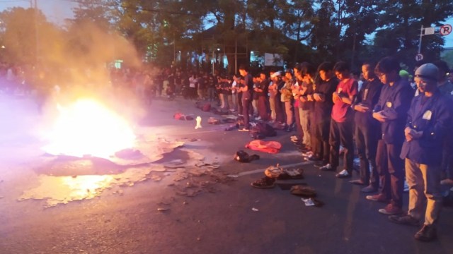 Mahasiswa salat Magrib di depan gedung DPRD Jabar di depan api yang membara. Foto: Rachmadi Rasyad/kumparan
