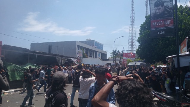 Massa aksi yang lain terlihat melindungi kepala mereka saat aksi mulai ricuh, dan batu mulai dilempari ke arah mobil water cannon. Foto: Rizal Syam/cermat